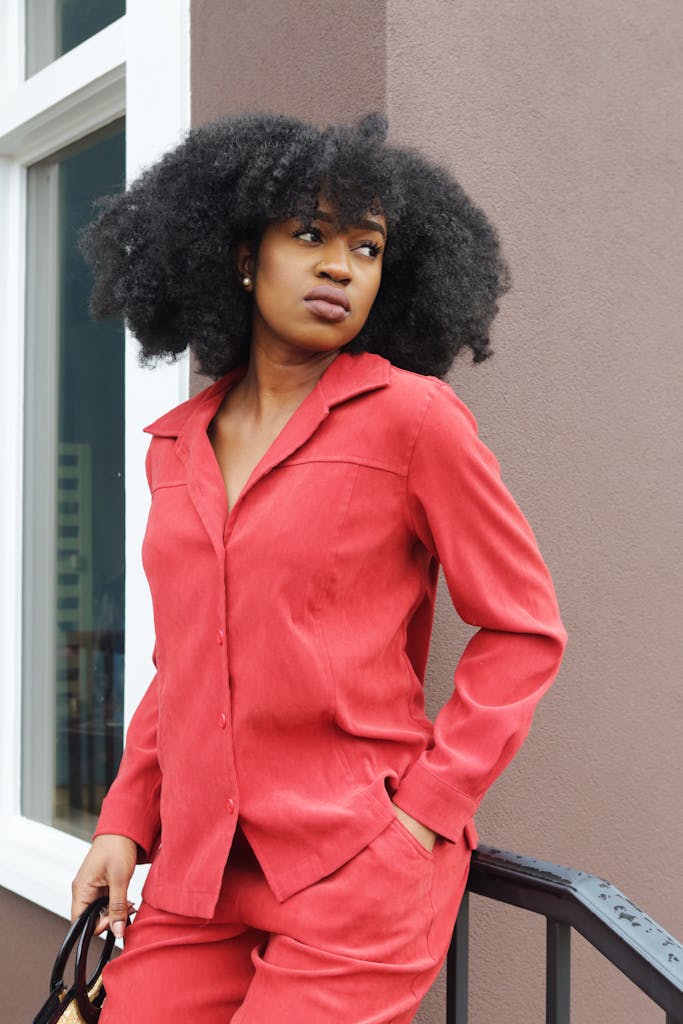 Woman in Red Dress Shirt and Pants Leans on Stair Railing