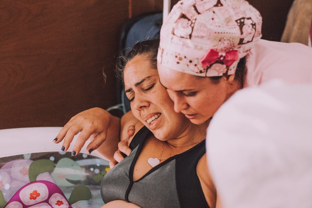 Austin Doula Services A midwife comforts a pregnant woman during a water birth at home.