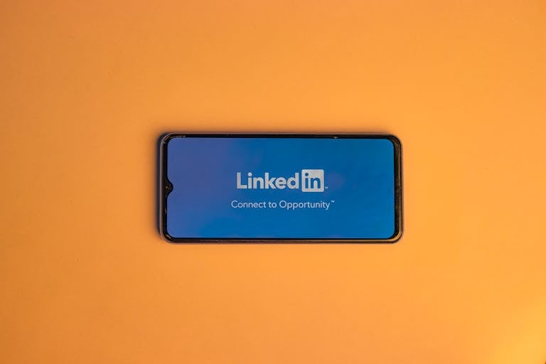 Smartphone showing LinkedIn login on vibrant orange background, symbolizing connectivity. Standout LinkedIn Profile