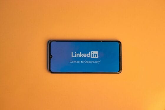 Smartphone showing LinkedIn login on vibrant orange background, symbolizing connectivity. Standout LinkedIn Profile
