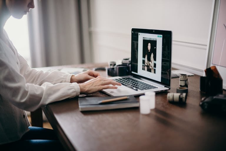 A freelancer working on a laptop in a cozy home office, focusing on creative design tasks. Professional Headshot Photographer in Austin