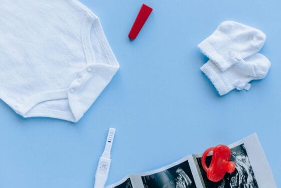 Baby Registry Checklist | Flat lay of baby essentials and a pregnancy test on a blue background.
