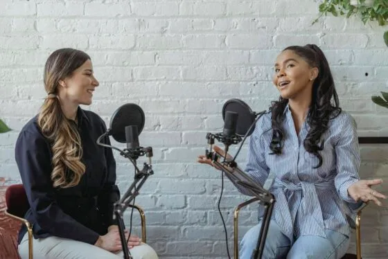 Best Personal Branding Photos for Speaking, Media & Podcasts 80 Personal branding photos for media Smiling African American female guest gesticulating while having interview with journalist sitting near mic