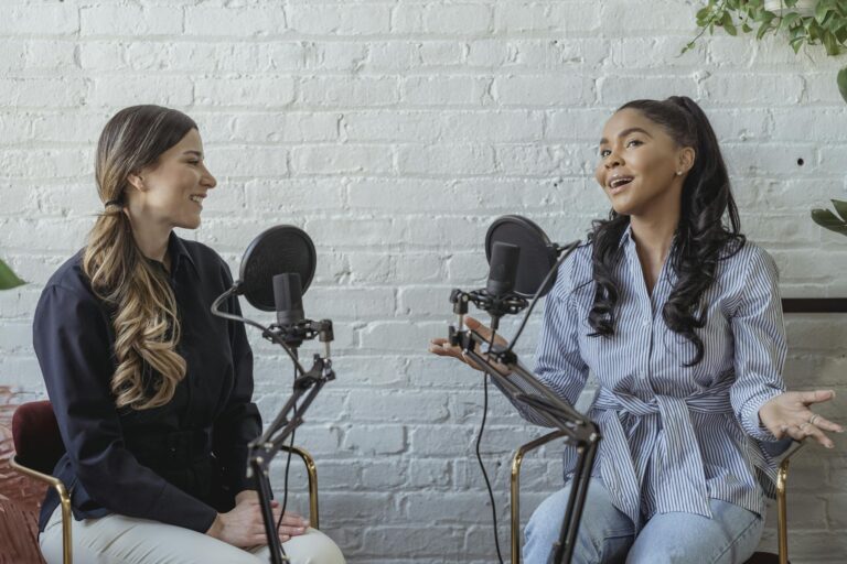 Personal branding photos for media Smiling African American female guest gesticulating while having interview with journalist sitting near mic