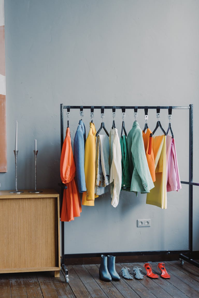 branding session outfit changes A vibrant clothes rack with colorful outfits in a minimalist room setting.