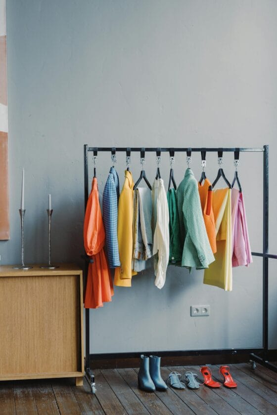 branding session outfit changes A vibrant clothes rack with colorful outfits in a minimalist room setting.