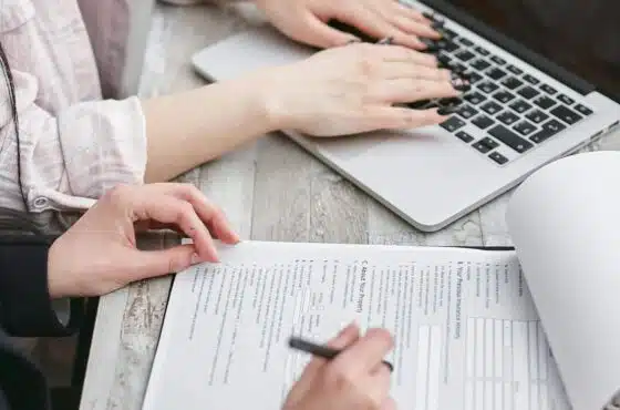 Go High Level vs HoneyBook: Which CRM Is Right for You 98 Go High Level vs HoneyBook Close-up of hands typing on a laptop and reviewing business documents, focused on finance and legal tasks.