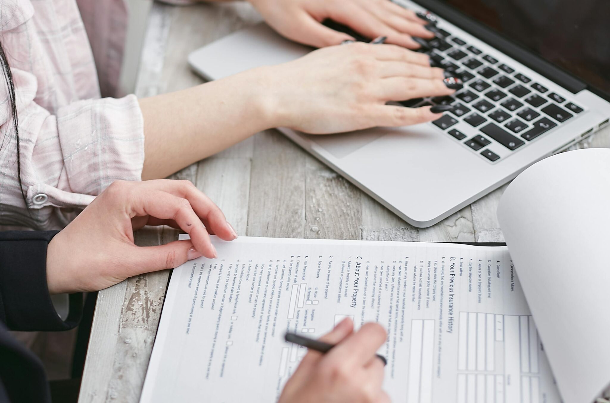 Go High Level vs HoneyBook Close-up of hands typing on a laptop and reviewing business documents, focused on finance and legal tasks.