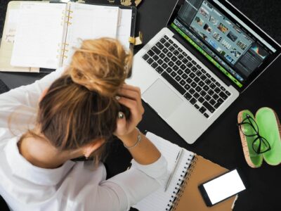 Small Business CRM: Top Features to Look for 96 small business CRM Overhead view of a stressed woman working at a desk with a laptop, phone, and notebooks.