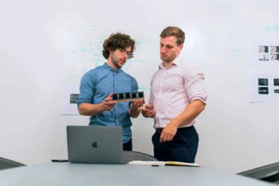 How to Plan Your Branding Session for Launch of a Product or Service 79 Two men in an office discussing and reviewing a tech prototype. Branding Session for Launch