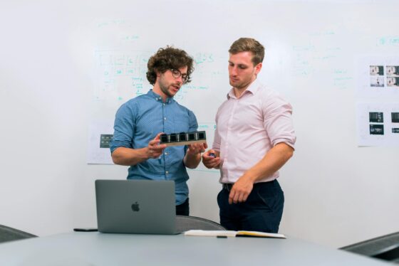 Two men in an office discussing and reviewing a tech prototype. Branding Session for Launch