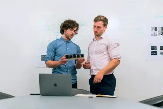 How to Plan Your Branding Session for Launch of a Product or Service 76 Two men in an office discussing and reviewing a tech prototype. Branding Session for Launch