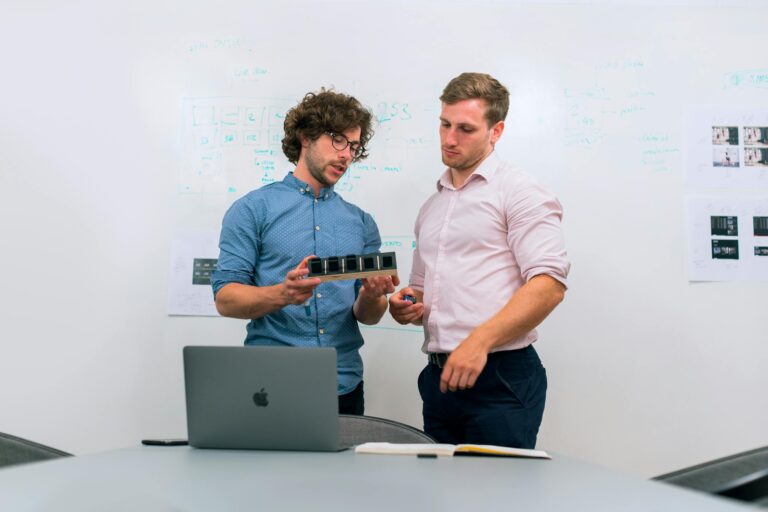 Two men in an office discussing and reviewing a tech prototype. Branding Session for Launch