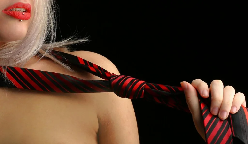 Boudoir birthday gift Close-up of a woman holding a red and black necktie, emphasizing sensuality and style.
