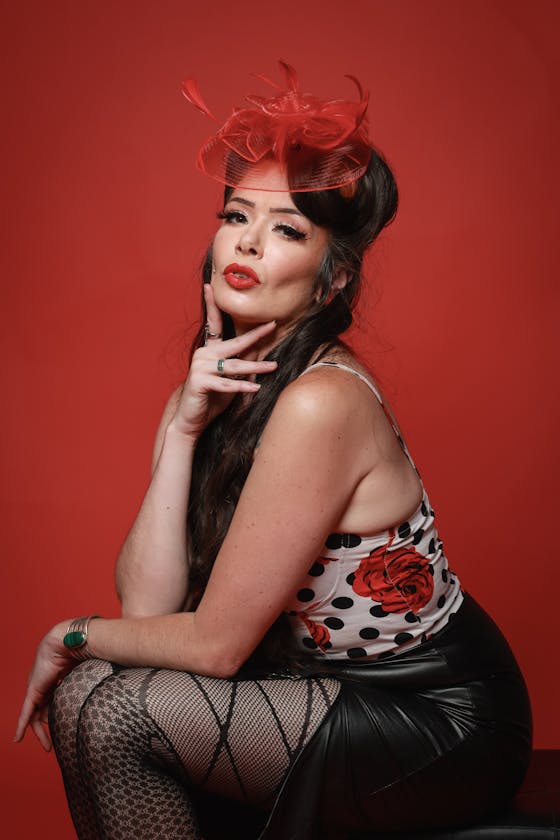 Vintage inspired boudoir photography Elegant portrait of a vintage pinup style model with red accents and floral patterns on a studio backdrop.