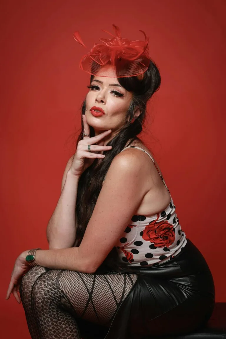 Vintage inspired boudoir photography Elegant portrait of a vintage pinup style model with red accents and floral patterns on a studio backdrop.