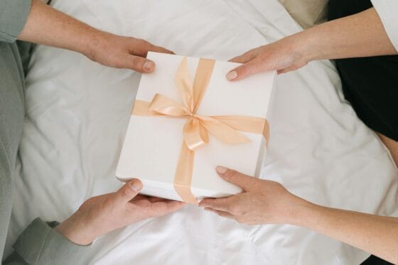 display boudoir images | Hands exchanging a beautifully wrapped gift box, symbolizing celebration and sharing.