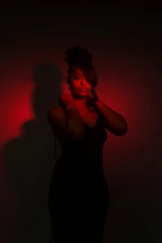 Celebrating Women of Color Boudoir Beauty 69 Celebrating Women of Color Boudoir A striking portrait of an elegant woman in a black dress, highlighted by dramatic red lighting.